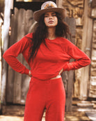Woman in a red outfit with a hat standing in front of a rustic wooden background